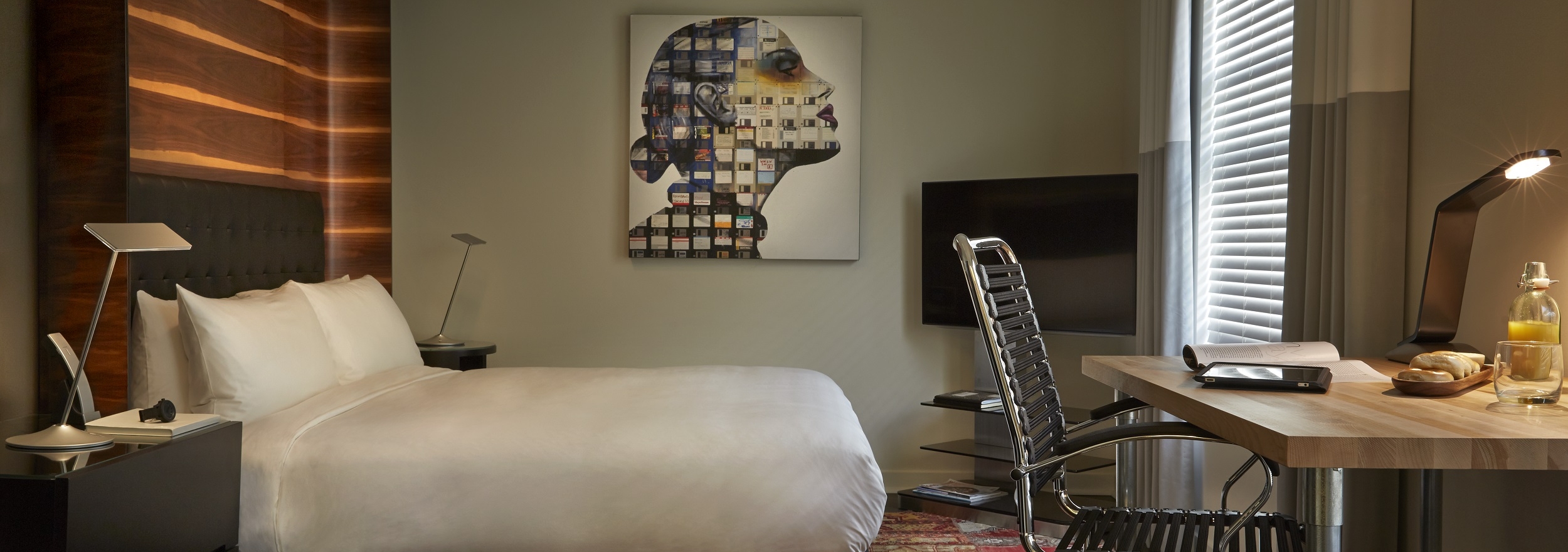Z Hotel in San Francisco Offer: Book Two Nights and Receive Your Third Night for Free, based on availability; Styled San Francisco hotel room with queen bed, work desk and modern collage of a woman hanging on wall.